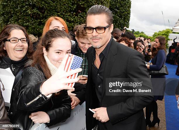 Brad Pitt signs autographs at a private reception as costumes and props from Disney's "Maleficent" are exhibited in support of Great Ormond Street...