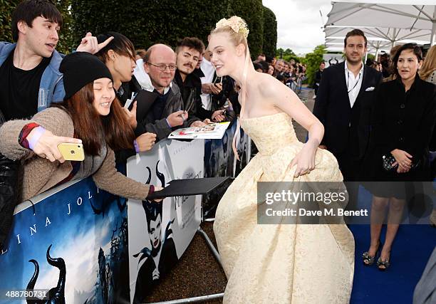 Elle Fanning signs autographs at a private reception as costumes and props from Disney's "Maleficent" are exhibited in support of Great Ormond Street...