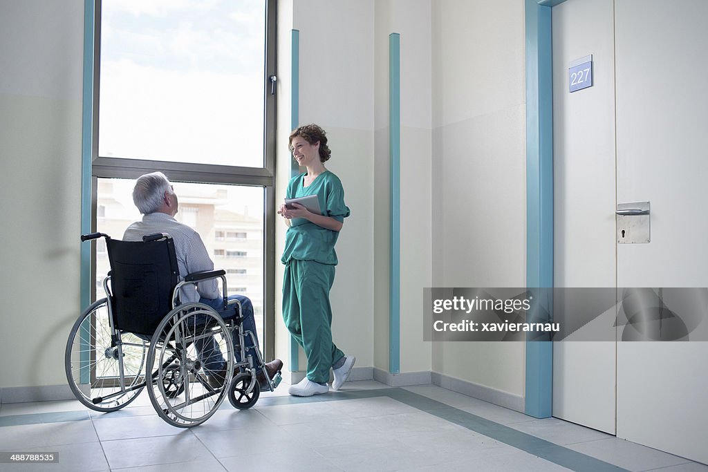 Nurse with patient on wheelchair having a talk
