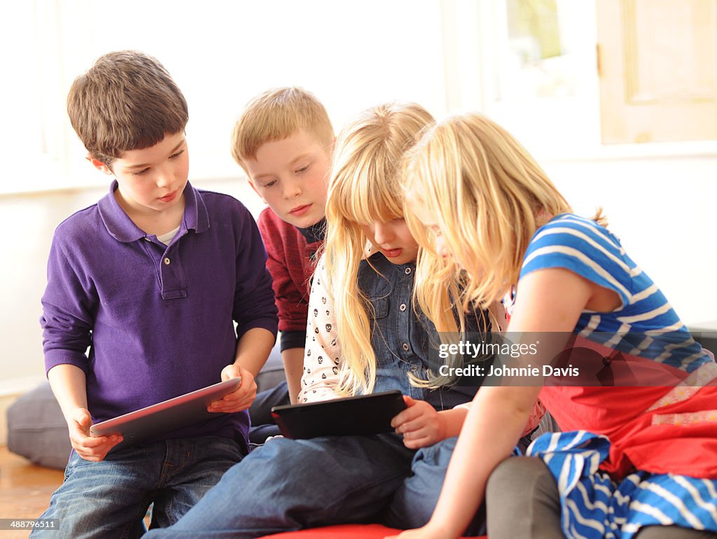Four children using digital tablets