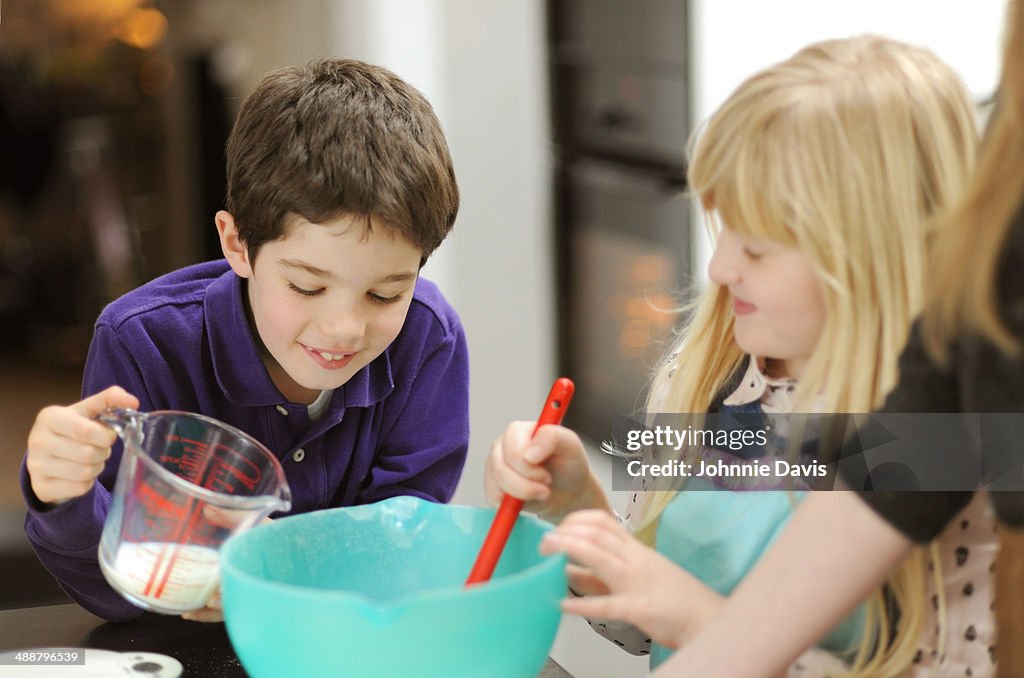 Boy and girl baking together with adults help