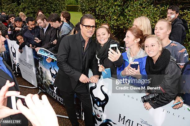 Brad Pitt signs autographs at a private reception as costumes and props from Disney's "Maleficent" are exhibited in support of Great Ormond Street...