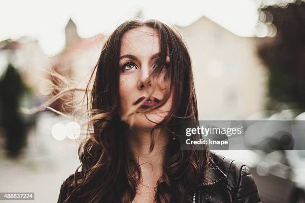 candid portrait of beautiful woman in wind - tossing hair facing camera woman outdoors stock pictures, royalty-free photos & images