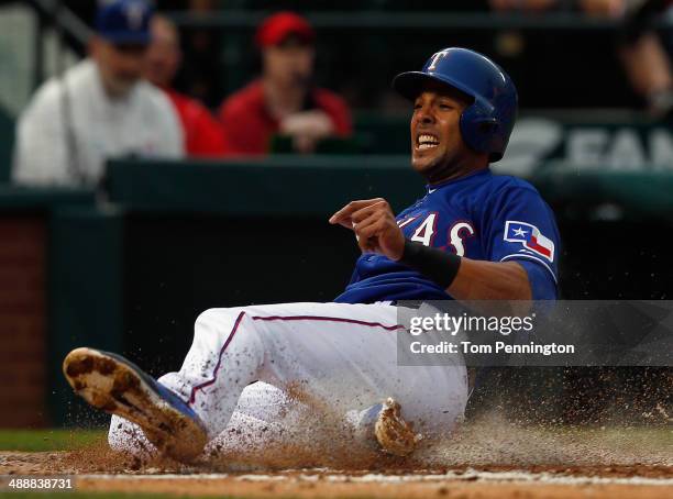 Alex Rios of the Texas Rangers slides into home plate against catcher Michael McKenry of the Colorado Rockies to score in the bottom of the second...