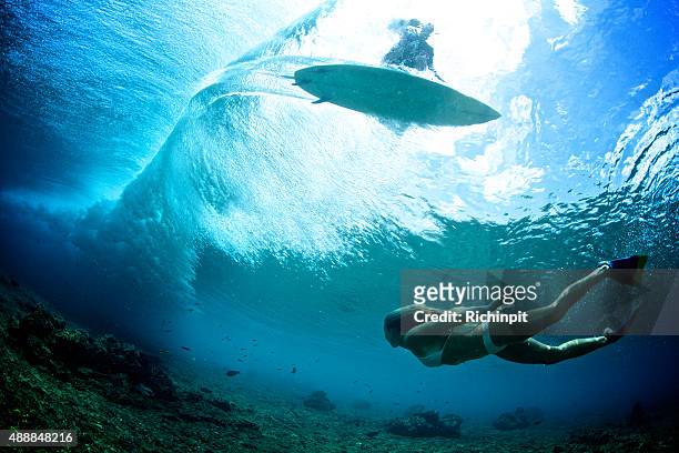ragazza nuota sotto il wave mentre surfista è sihlouetted sopra - maldives sport foto e immagini stock