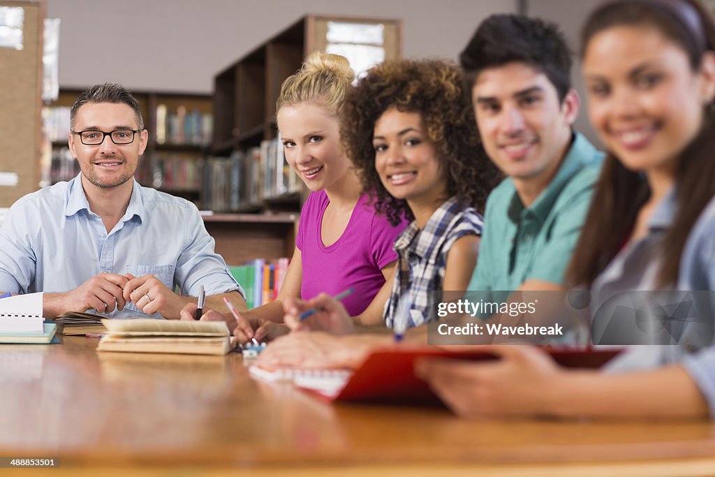 Professor and students at table in library
