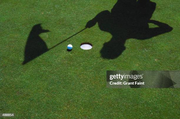 shadow of golfer & flag at hole with ball - golfplatz-green stock-fotos und bilder