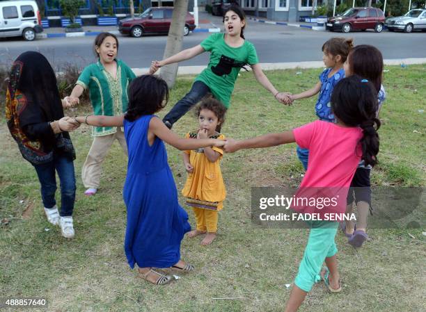 Picture taken on September 17, 2015 shows a group of Syrian migrants with their children sitting in a park of the Moroccan town of Nador where around...