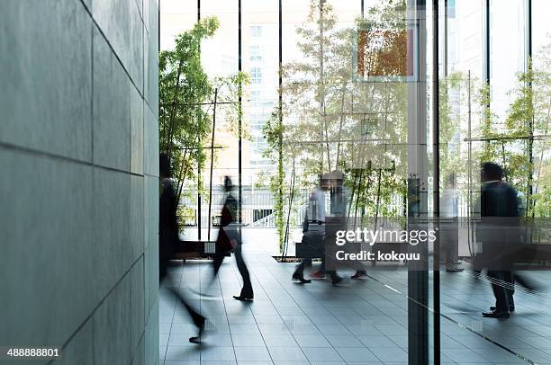 geschäftsmann zu fuß in einen städtischen gebäude - eingangshalle büro modern stock-fotos und bilder