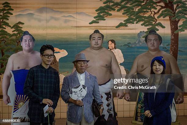 Spectators pose for pictures in front of cardboard cutouts of sumo wrestlers during the Tokyo Grand Sumo tournament at the Ryogoku Kokugikan on...