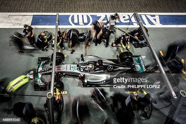 Mercedes AMG Petronas F1 Team's British driver Lewis Hamilton sits in his car at a pit stop during the practice session of the Formula One Singapore...
