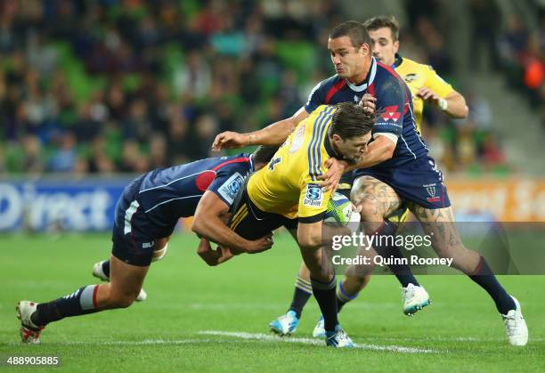 Cory Jane of the Hurricanes is tackled by Tom English and Tamati Ellison of the Rebels during the round 13 Super Rugby match between the Rebels and...