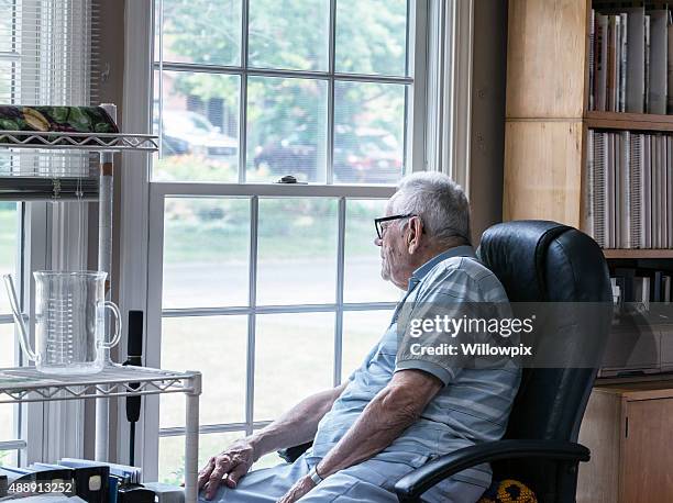 curious senior man looking through window - old man alone stock pictures, royalty-free photos & images