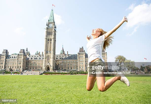 cheerful young woman at ottawa parliament jumping high up - ottawa park stock pictures, royalty-free photos & images