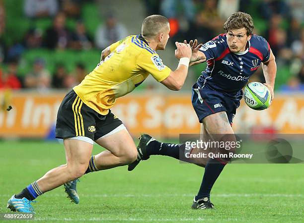 Luke Burgess of the Rebels fends off a tackle during the round 13 Super Rugby match between the Rebels and the Hurricanes at AAMI Park on May 9, 2014...