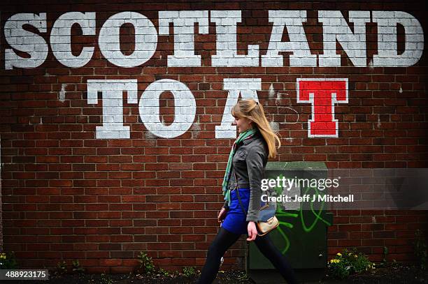 Woman walks past stencilling on a wall in the East End of the city advertising a well known Scottish lager on May 8, 2014 in Glasgow, Scotland.A...