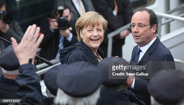 German Chancellor Angela Merkel and French President Francois Hollande greet a sailors' choir before boarding a boat to tour the nearby chalk cliffs...