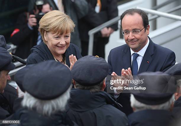 German Chancellor Angela Merkel and French President Francois Hollande greet a sailors' choir before boarding a boat to tour the nearby chalk cliffs...