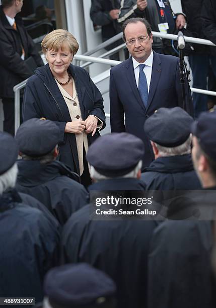 German Chancellor Angela Merkel and French President Francois Hollande greet a sailors' choir before boarding a boat to tour the nearby chalk cliffs...