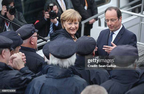 German Chancellor Angela Merkel and French President Francois Hollande greet a sailors' choir before boarding a boat to tour the nearby chalk cliffs...