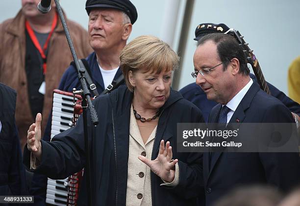 German Chancellor Angela Merkel explains a sailor's song to French President Francois Hollande while the two listen to a sailors' choir before...