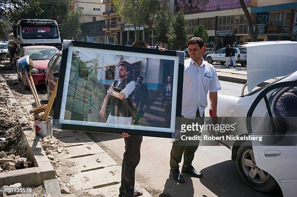 Framed picture of former mujahideen leader Ahmad Shah Massoud is carried to a car August 30, 2015 in Kabul, Afghanistan. A political and military...