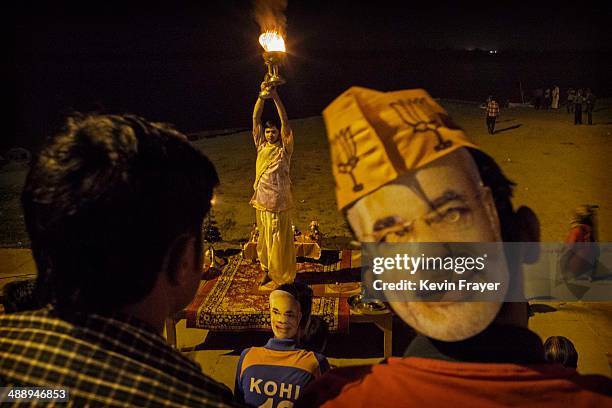 Hindu Brahmin Priest performs the evening Ganga Aarti as devotees wear masks showing BJP leader Narendra Modi at Assi Ghat on the Ganges River on May...