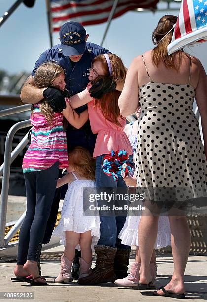 Coast Guard 2nd Class Josh Coaker is greeted by his daughters, Hope Coaker and Hannah Coaker and Harper Coaker as his wife, Carissa Coaker, looks on...