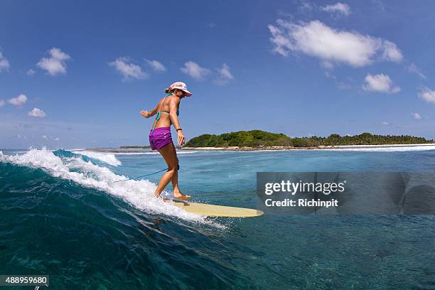 surfer girl rides a longboard in the tropics - board shorts stock pictures, royalty-free photos & images