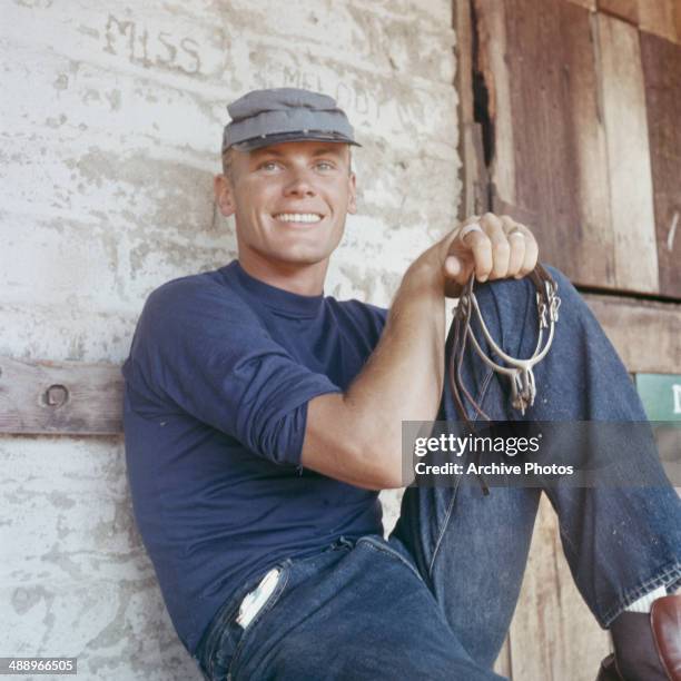 American actor Tab Hunter holding a pair of stirrups, circa 1960.