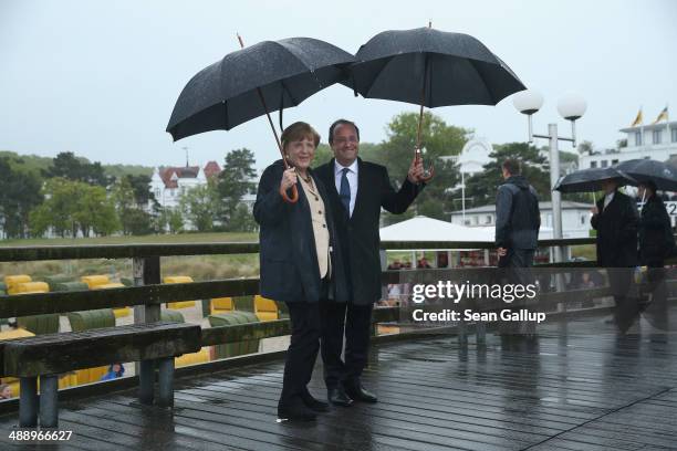 German Chancellor Angela Merkel and French President Francois Hollande walk under umbrellas and rain on a pier on Ruegen Island on May 9, 2014 in...