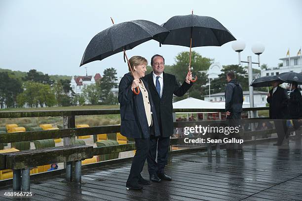 German Chancellor Angela Merkel and French President Francois Hollande walk under umbrellas and rain on a pier on Ruegen Island on May 9, 2014 in...