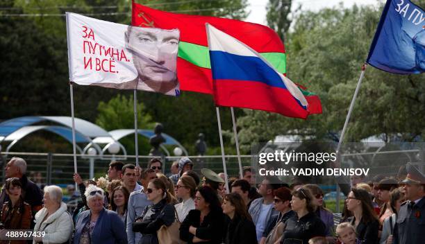 People carry a Russian flag and a flag with a portait of Russia's President Vladimir Putin reading "We are for Putin!" in Tiraspol, the main city of...