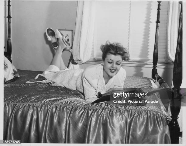 Portrait of actress Angela Lansbury, lying on a hotel bed wearing a bathrobe, circa 1955-1965.