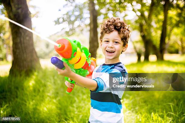 boy playing with squirt gun - waterpistool stockfoto's en -beelden