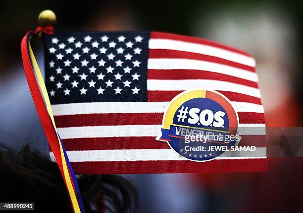 Protester holds up a miniature US flag with a sticker on it during a demonstration in front of the White House in Washington, DC, on May 9, 2014...