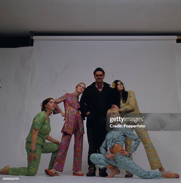 Portrait of the models Twiggy, Joanna Lumley, Joy Rance and Vicky Hodge in a studio modeling multicoloured two piece trouser suits surrounding a man...