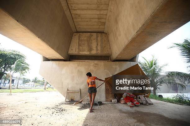 Viviane Sabino de Souza sweeps outside her makeshift dwelling beneath a stretch of the Transcarioca BRT highway being constructed on May 9, 2014 in...