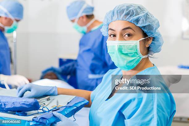 hispanic surgical nurse or technician assisting with surgery in hospital - 手術用具 個照片及圖片檔