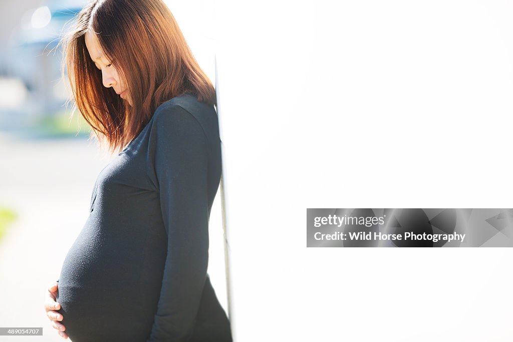 Pregnant woman looking at her belly in sunshine