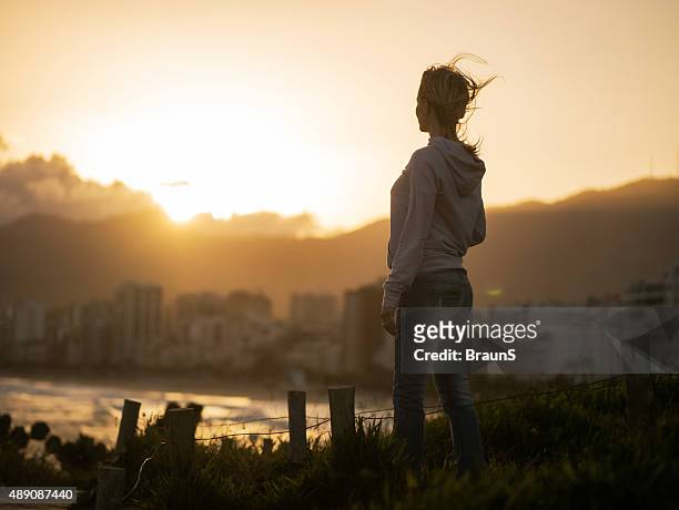 young woman looking at beach view at sunset. - standing water stockfoto's en -beelden
