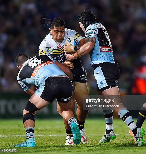 John Asiata of the Cowboys is tackled by Michael Ennis and Chris Heighington of the Sharks during the Second NRL Semi Final match between the North...