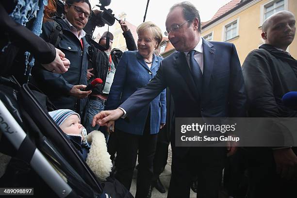 French President Francois Hollande and German Chancellor Angela Merkel greet a baby named Jonathon while the two leaders toured the city center on...