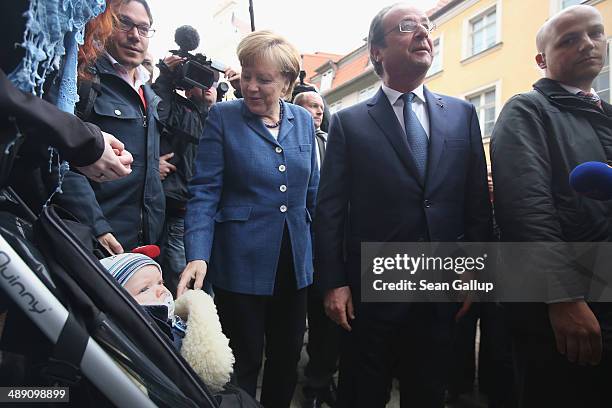 French President Francois Hollande and German Chancellor Angela Merkel greet a baby named Jonathon while the two leaders toured the city center on...