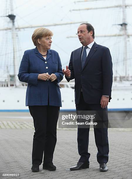 French President Francois Hollande and German Chancellor Angela Merkel chat in front of the Gorch Fock I tall ship while the two leaders toured the...