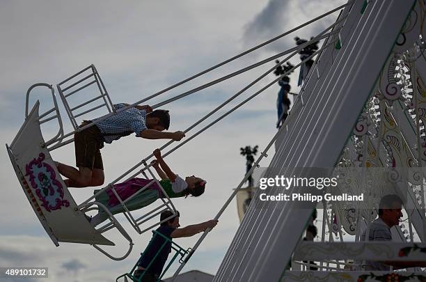 Revellers enjoy their ride on swingboats on the "Oide Wiesn" historical Oktoberfest on the opening day of the 2015 Oktoberfest on September 19, 2015...