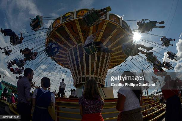 Revellers enjoy their ride with a vintage caroussel on the "Oide Wiesn" historical Oktoberfest on the opening day of the 2015 Oktoberfest on...