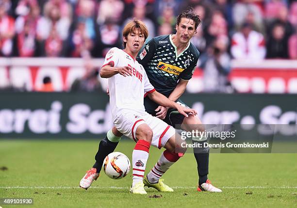 Yuya Osako of 1. FC Koeln is challenged by Roel Brouwers of Borussia Moenchengladbach during the Bundesliga match between 1. FC Koeln and Borussia...