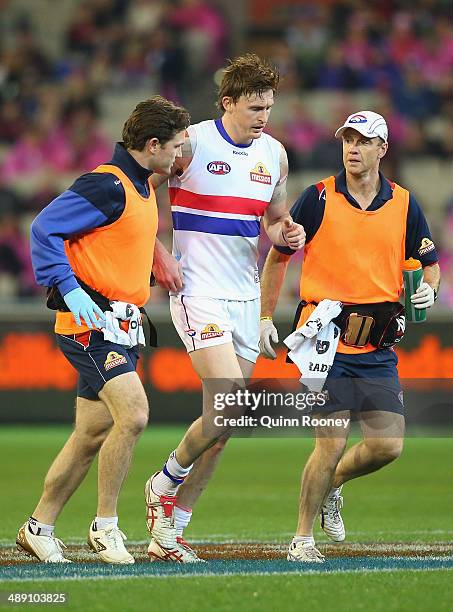 Tom Williams of the Bulldogs is helped off the ground by trainers during the round eight AFL match between the Melbourne Demons and the Western...