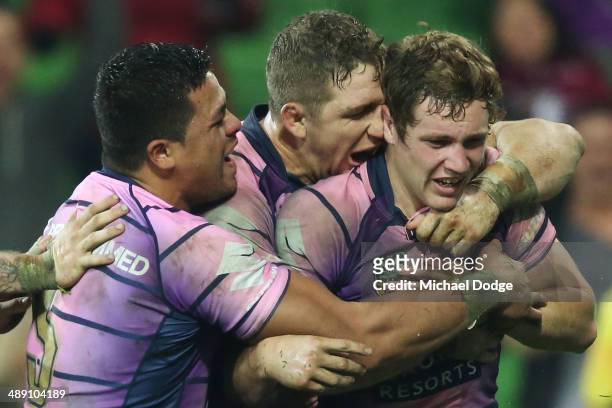 Kurt Mann of the Storm is hugged by Young Tonumaipea and Ryan Hoffman after scoring a try during the round nine NRL match between the Melbourne Storm...